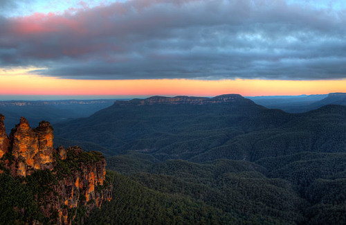 The Late afternoon sun sets in the west casting the final light onto the rock faces of the Three Sisters, Katoomba, NSW, Australia