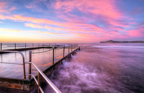 The sky lights up pink and blue in a spectacular surmise at Mona Vale Tidal Pool, NSW, Australia